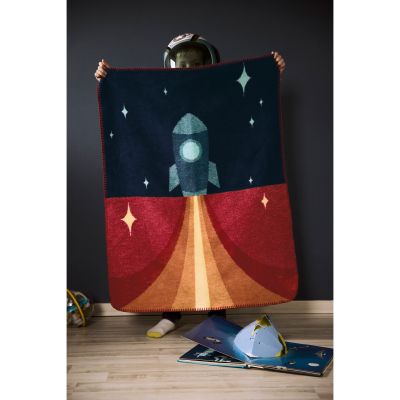 Babydecke Little Rocket wird im Kinderzimmer hochgehalten und zeigt eine Rakete vor dunkelblauem Sternenhimmel.