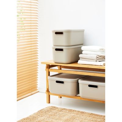 Mehrere beige Aufbewahrungsboxen mit Deckeln auf einem Möbelstück im Wohnraum