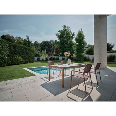 Mehrere Gartenstühle mit Armlehnen an einem rechteckigen Tisch auf einer Terrasse neben einem Pool