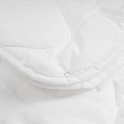 Nahaufnahme einer weißen Steppdecke mit sichtbarer Steppung und Druckknopf am Rand