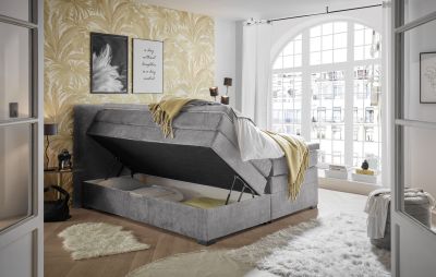 Boxspringbett „Vogue 15 grey“ in einem Schlafzimmerambiente, Bettkasten geöffnet, dekoriert mit Kissen und Bettdecke