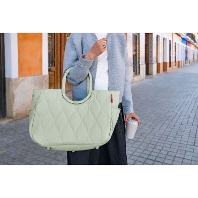 Shopper mit Ringgriffen von Reisenthel, Modell Loopshopper L, in Hellgrün mit Steppstruktur, von einer Person an den ovalen Ringgriffen getragen