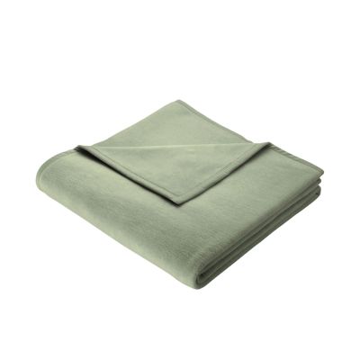 Gefaltete Wohndecke Cotton Home Salbei in gedecktem Hellgrün mit schmal eingefasster Kante auf weißem Hintergrund.