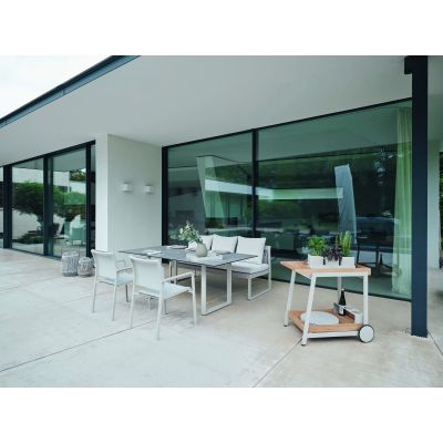 Gartenmöbel Set mit Tisch, Stühlen und Sitzbank auf einer überdachten Terrasse vor einer Glasfassade