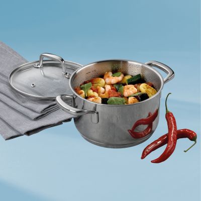 Geöffneter Fleischtopf mit Gemüsegericht neben Glasdeckel, Küchentuch und roten Chilischoten auf hellblauem Hintergrund