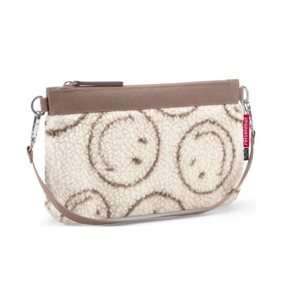 Kleine Umhängetasche von Reisenthel, Modell Mini Pouch, in Creme und Braun mit Smiley-Muster aus Teddyfleece, schräg von vorn mit Schultergurt und Reißverschluss
