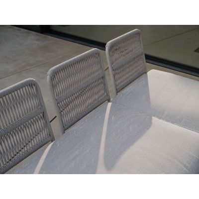 Detailaufnahme der oberen Rückenlehne eines Outdoor Sofas mit geflochtener Struktur und Sitzpolster im Vordergrund.