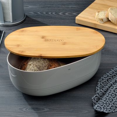 Dunkelgrauer Brotkasten mit angehobenem Holzdeckel und eingelegtem Brot auf einer dunklen Arbeitsplatte