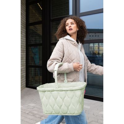 Einkaufskorb von Reisenthel, Modell Carrybag, in Hellgrün mit Steppstruktur, von einer Person am Tragegriff getragen