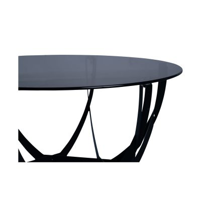 Nahaufnahme der dunklen runden Glasplatte eines Couchtischs mit geschwungenem schwarzen Metallgestell, vor weißem Hintergrund fotografiert