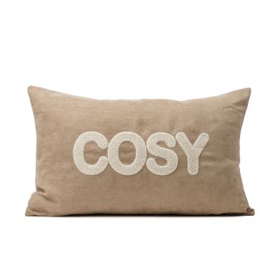 Beigefarbene Kissenhülle mit dem weißen Schriftzug „COSY“, ca. 30 × 50 cm.
