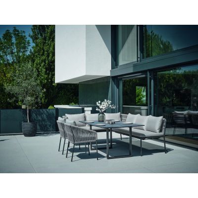 Eine alternative Ansicht einer Sitzgruppe aus Gartenbänken und Stühlen auf einer Terrasse vor einem modernen Gebäude.