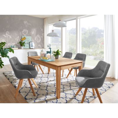Rechteckiger Esstisch aus Holz mit mehreren Stühlen in einem hellen Esszimmer mit Teppich und Fenstern