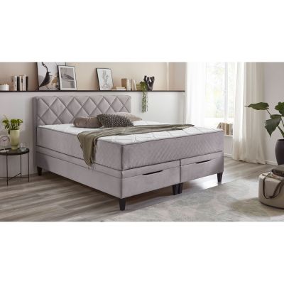 Boxspringbett mit fest vernähtem Matratzentopper in einem eingerichteten Schlafzimmer