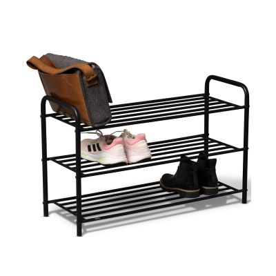 Schwarzes dreistufiges Metallregal mit einer braunen Tasche auf der oberen Ablage, weißen Sportschuhen auf der mittleren Ebene und schwarzen Stiefeletten auf der unteren Ebene vor weißem Hintergrund