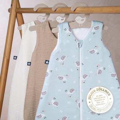 Hellblauer Babyschlafsack mit Tiermotiv hängend zwischen weiteren Schlafsäcken 