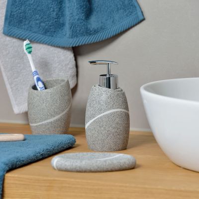 Beiger Seifenspender auf einer Holzablage neben Zahnputzbecher Seifenschale Zahnbürsten und Waschbecken
