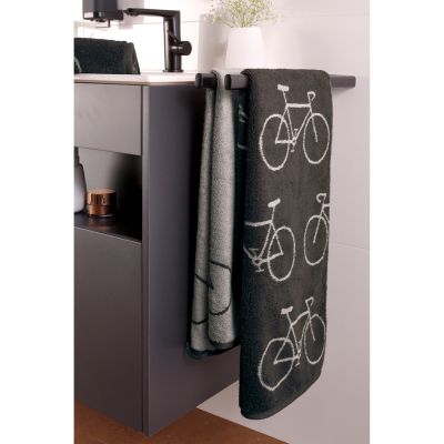 Dunkle Velo-Handtücher mit Fahrradmotiven hängen an einem grauen Badmöbel, daneben ein helleres Tuch.