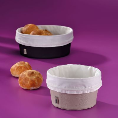 Silbergrauer und dunkler Brotkorb mit weißen Stoffeinsätzen neben mehreren Brötchen auf einer violetten Fläche
