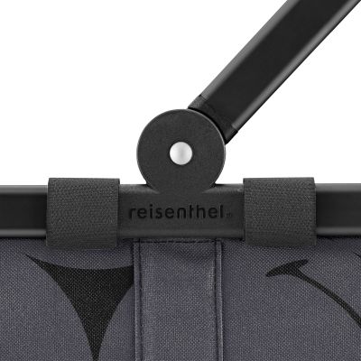 Einkaufskorb von Reisenthel, Modell Carrybag, in Grau mit großflächigem Smiley-Muster, als Nahaufnahme des Gelenks am Aluminiumgriff.