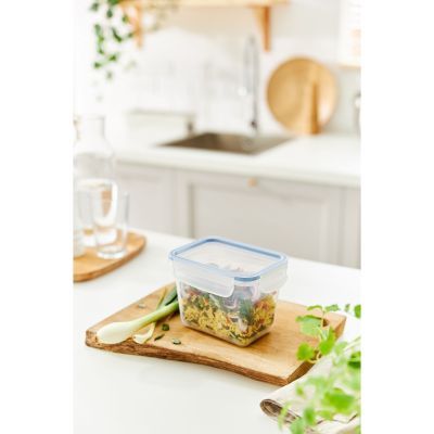 Transparente Frischhaltedose mit Lebensmitteln auf einem Holztablett in einer Küche