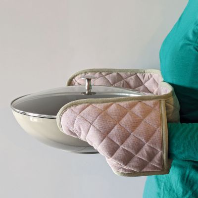 Eine Person hält einen heißen Metalltopf mit dem doppelten Ofenhandschuh an beiden Griffen