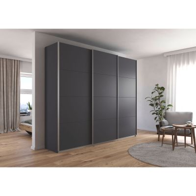 Großer grau-metallicer Schwebetürenschrank in einem hell eingerichteten Schlafzimmer mit Holzfußboden und Sitzbereich