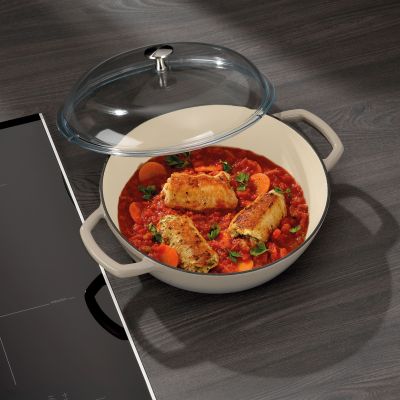 Hellgraue Bauernpfanne mit zubereitetem Tomaten Gemüsegericht und angehobenem Glasdeckel auf einem Backofenrost