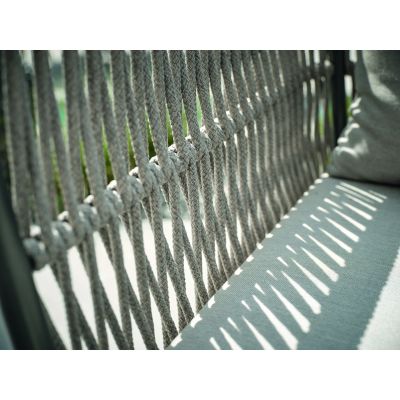 Nahaufnahme der geflochtenen Rückenlehne einer Gartenbank, mit Schattenlinien auf der Sitzfläche.
