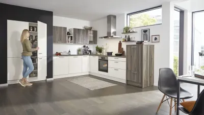 Moderne Küche mit dunklen Holzfronten und weißen Schrankflächen, Frau öffnet Küchenschrank