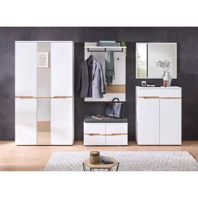 Eingestellter Garderobenbereich mit weißem Schrank, weißem Wandpaneel, Sitzbank und Kommode vor dunkler Wand, ergänzt durch Kleidung und Dekoration.