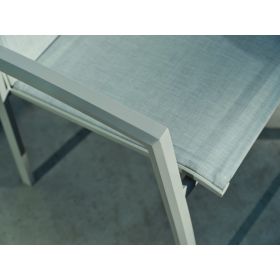 Nahaufnahme der Armlehne und der textilen Sitzfläche eines Gartenstuhls, fotografiert im Außenbereich.
