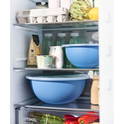 Blaue Rührschüsseln mit transparentem Deckel auf Ablagen in einem Kühlschrank