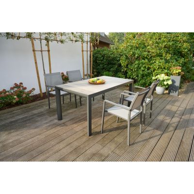 Gartentisch mit Holzdekor-Platte und mehreren Stühlen auf einer Holzterrasse im Garten, von Pflanzen umgeben.