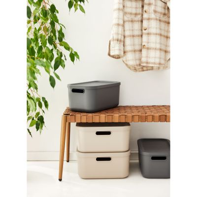 Mehrere Aufbewahrungsboxen mit Deckeln unter einem Tisch im Wohnraum