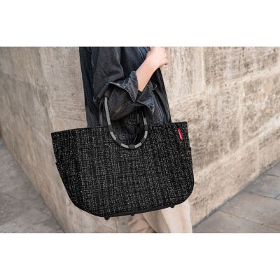 Shopper mit Ringgriffen von Reisenthel, Modell Loopshopper L, in Schwarz mit Bouclé-Struktur, von einer Person an den ovalen Ringgriffen getragen