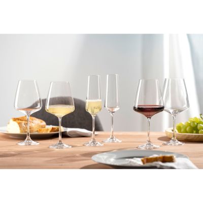 Mehrere Weingläser mit Weißwein Rotwein und Sekt auf einem gedeckten Tisch mit Brot und Trauben