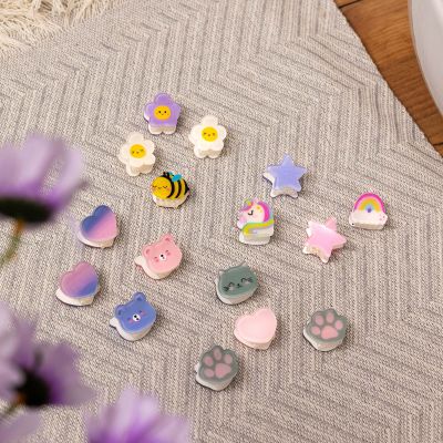 Haarspangen-Set, 4 Stück – Biene von Legami: Verschiedene kleine Haarspangen auf einem gestrickten Stoff.