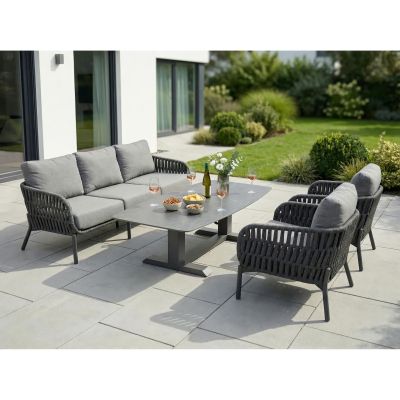 rechteckiger Gartentisch mit Sitzmöbeln auf einer Terrasse mit Garten im Hintergrund