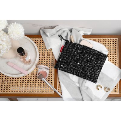 Reißverschlusstasche von Reisenthel, Modell Case 1, in Schwarz mit Bouclé-Struktur, auf einer Ablage neben Textilien und Dekoration platziert