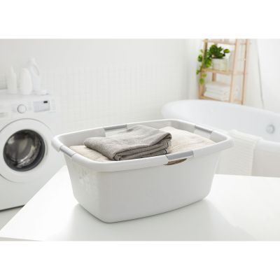 Graue Wäschewanne aus Kunststoff auf einem Tisch im Badezimmer neben einer Waschmaschine
