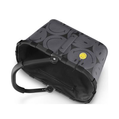 Einkaufskorb von Reisenthel, Modell Carrybag, in Grau mit großflächigem Smiley-Muster, auf die Seite gelegt mit sichtbarem Rahmen und eingeklapptem Griff.