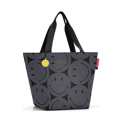 Shopper von Reisenthel, Modell Shopper M, in Grau mit großflächigem Smiley-Muster, frontal mit zwei langen Tragegriffen und gelbem Smiley-Anhänger.