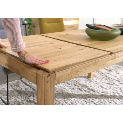 Person schiebt die Tischplatten eines ausziehbaren Esstisches aus Holz zusammen