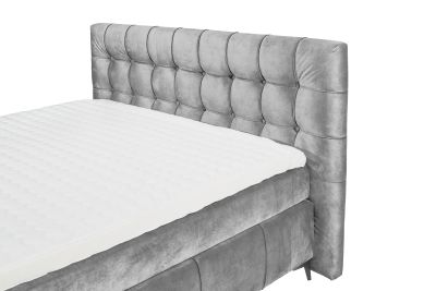 Boxspringbett in grauem Bezug, schräg aufgenommen, Fokus auf Kopfteil und Matratze, ohne Kissen