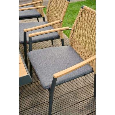 Gartenstuhl mit Polyrattan-Rückenlehne, Holzarmlehnen und dunkelgrauem Sitzpolster, auf einer Terrasse neben einem Tisch platziert