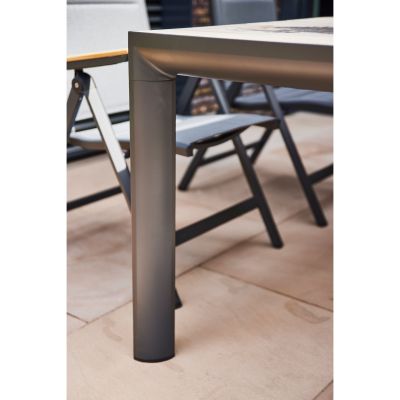Nahaufnahme eines runden Tischbeins aus grauem Aluminium mit glatter Oberfläche auf heller Terrassenfliese.