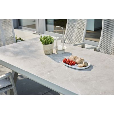 Tischplatte eines Gartentisches mit Pflanze und Geschirr im Außenbereich