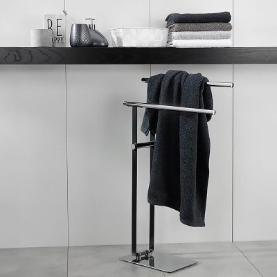 Dunkelgraues Duschtuch hängt über einem schmalen schwarzen Handtuchständer in einem hell gestalteten Badezimmer