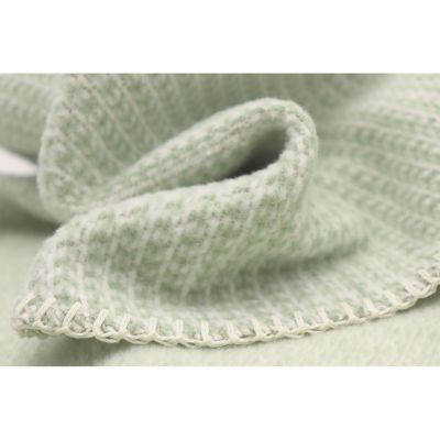 Nahaufnahme der Babydecke Cotton green mit weicher Stofffalte und fein umketteltem Rand.